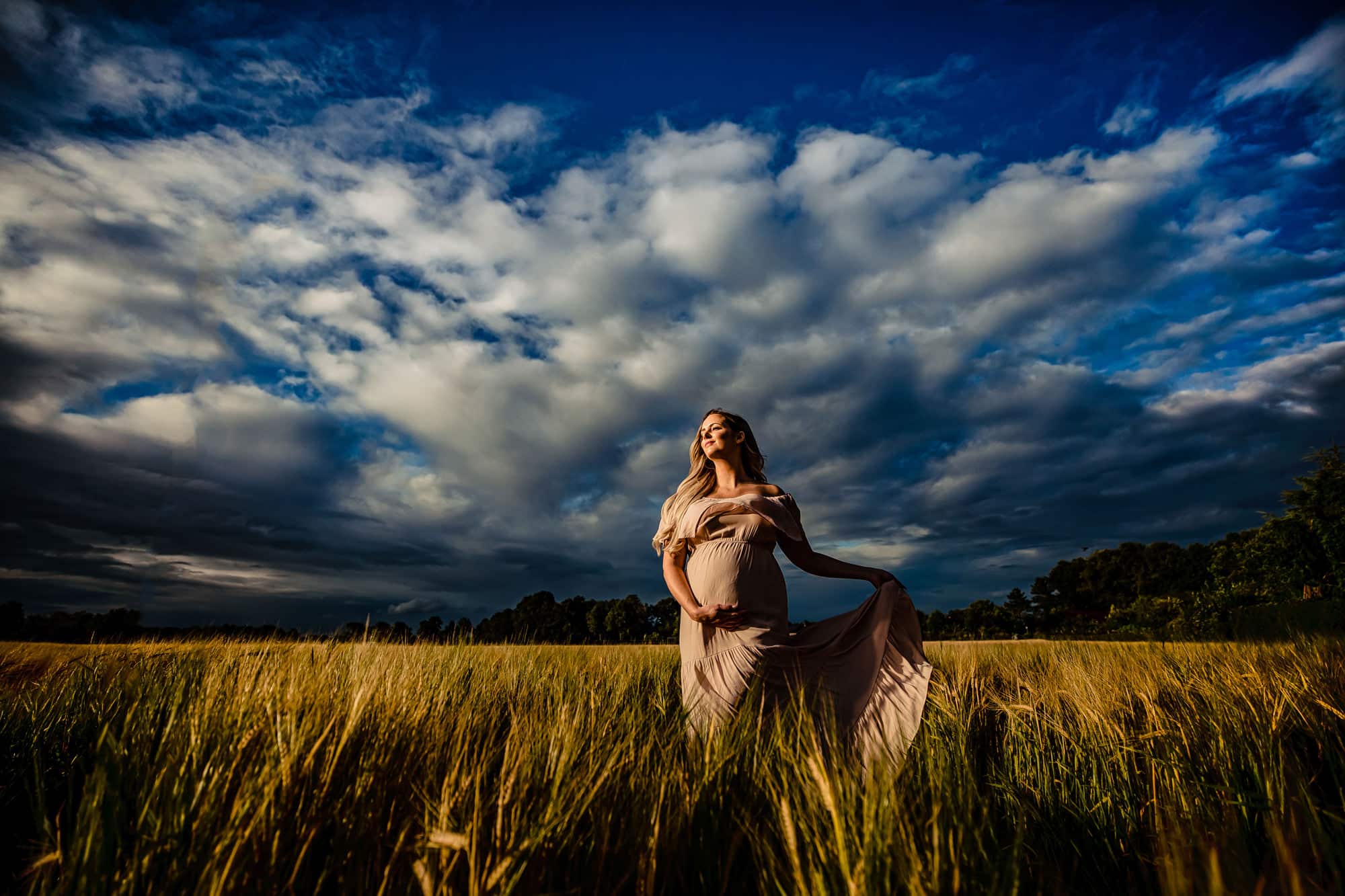Een speels tafereel waarbij toekomstige ouders samen een paar babykleertjes vasthouden, vol vreugde en verwachting.